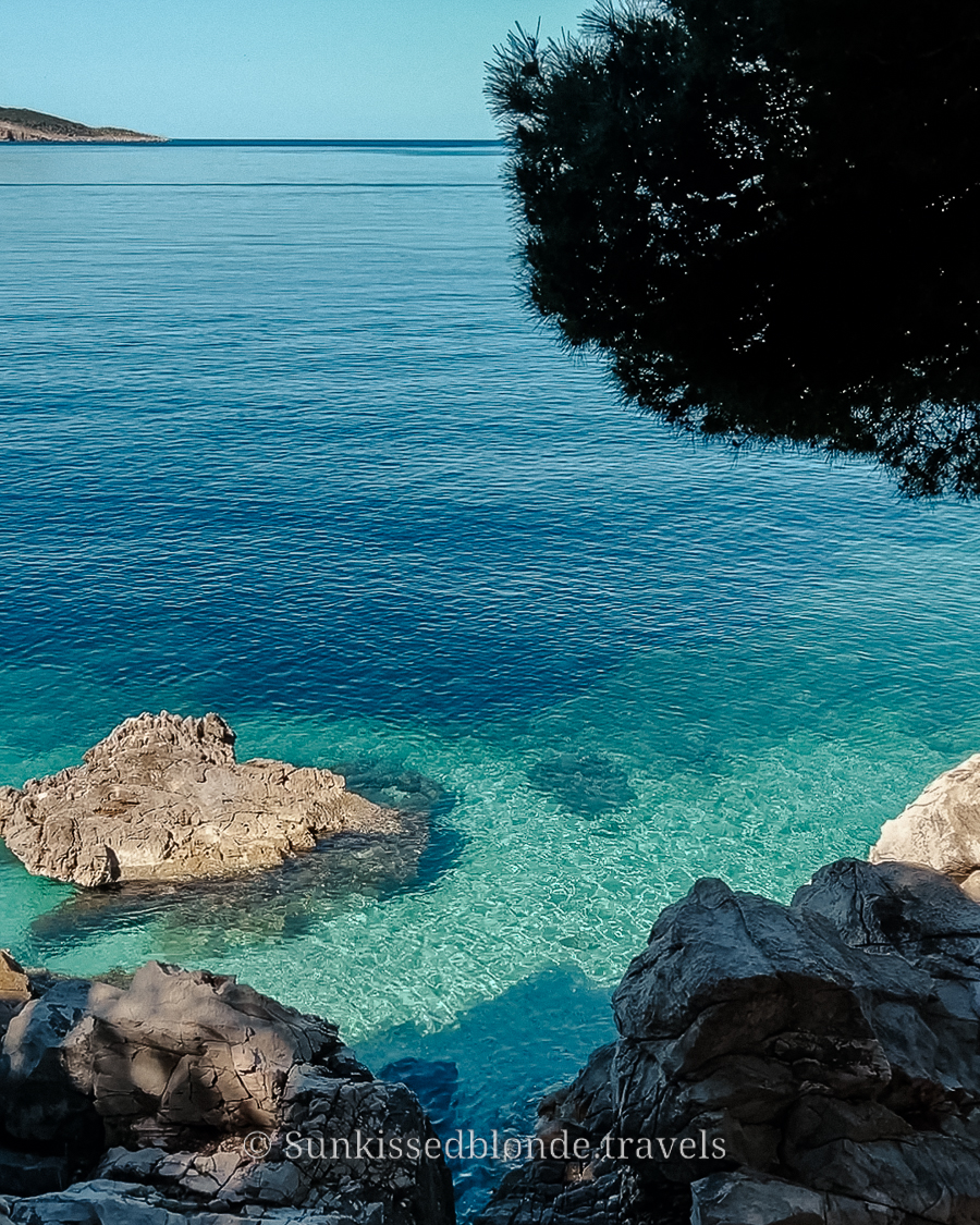 Crystal‑clear turquoise water along the rocky coastline near Split, Croatia, with sunlit shallows and rugged stone formations.