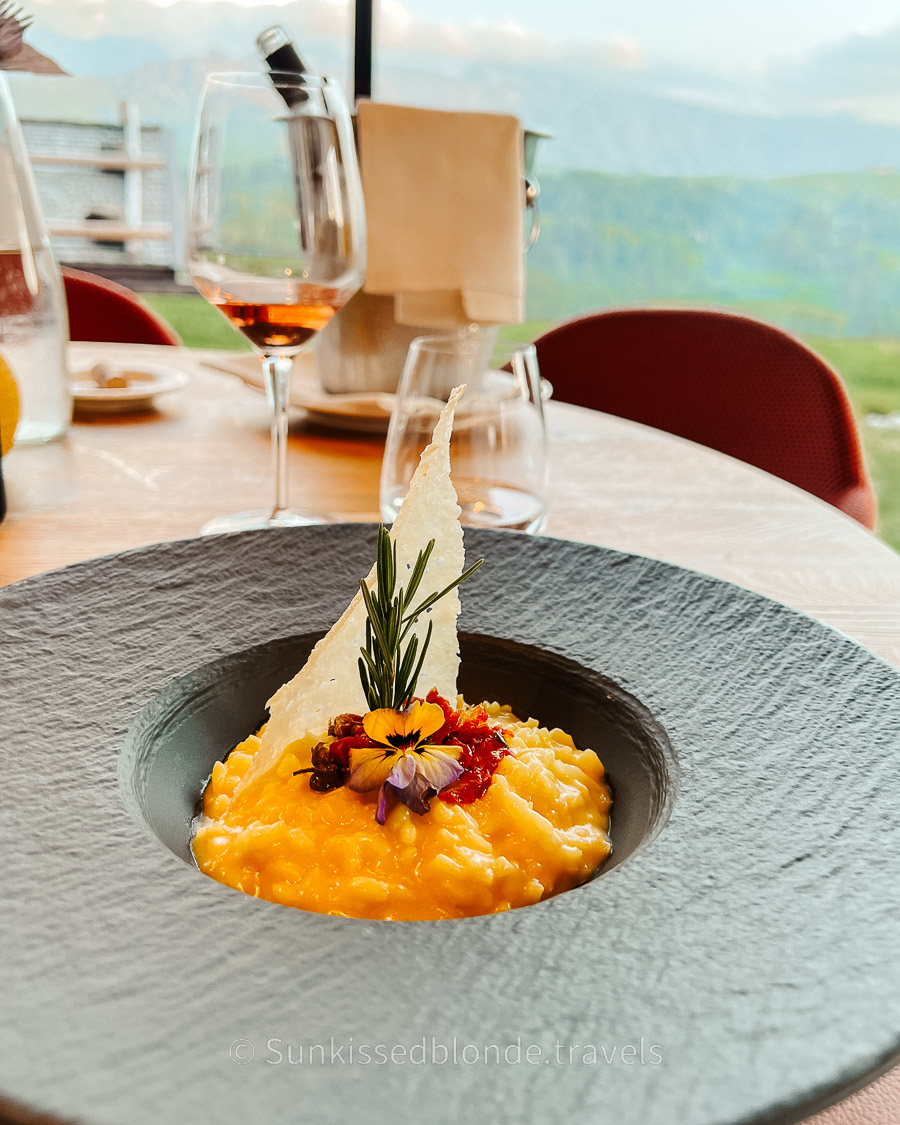 Gourmet dish at a South Tyrol hotel restaurant with floor-to-ceiling views over the Alpe di Siusi meadows and Dolomite peaks, Seiser Alm, Italy