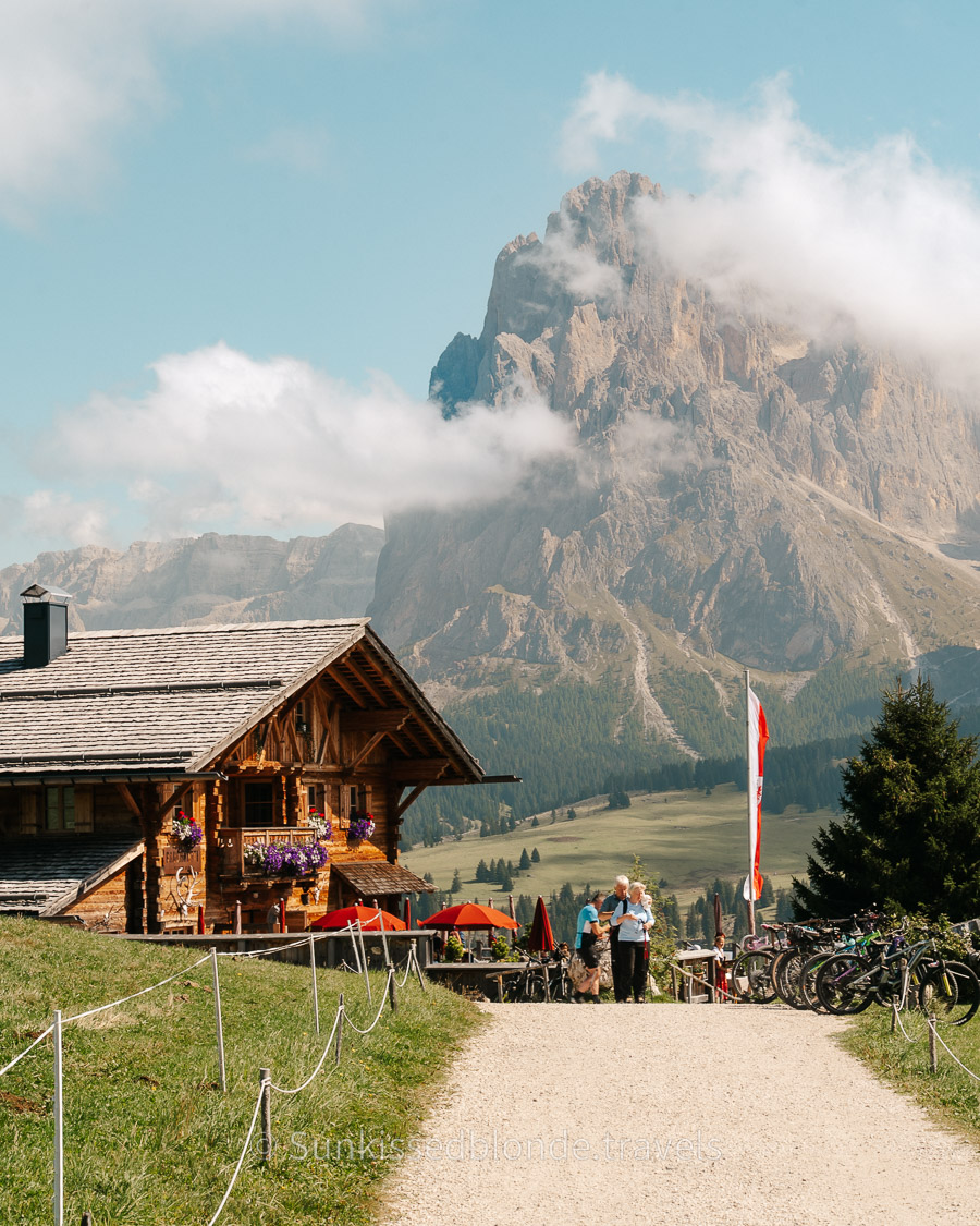 Hikers resting at a traditional mountain h&uuml;tte on Alpe di Siusi with sweeping views across the Dolomites, South Tyrol, Italy