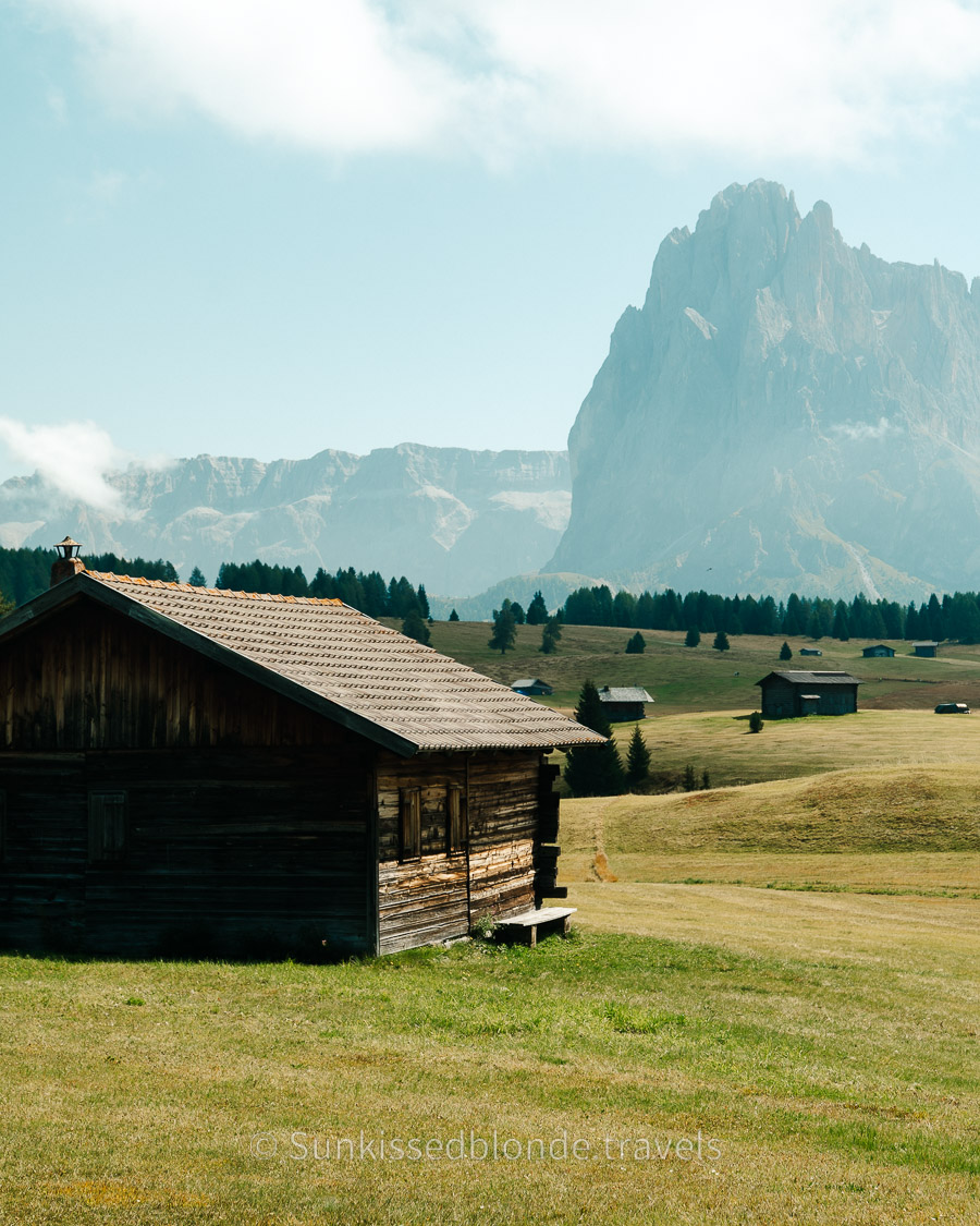 huts at Golden hour light over Alpe di Siusi alpine meadow with Sassolungo mountain peaks in the background, Dolomites, South Tyrol, Italy
